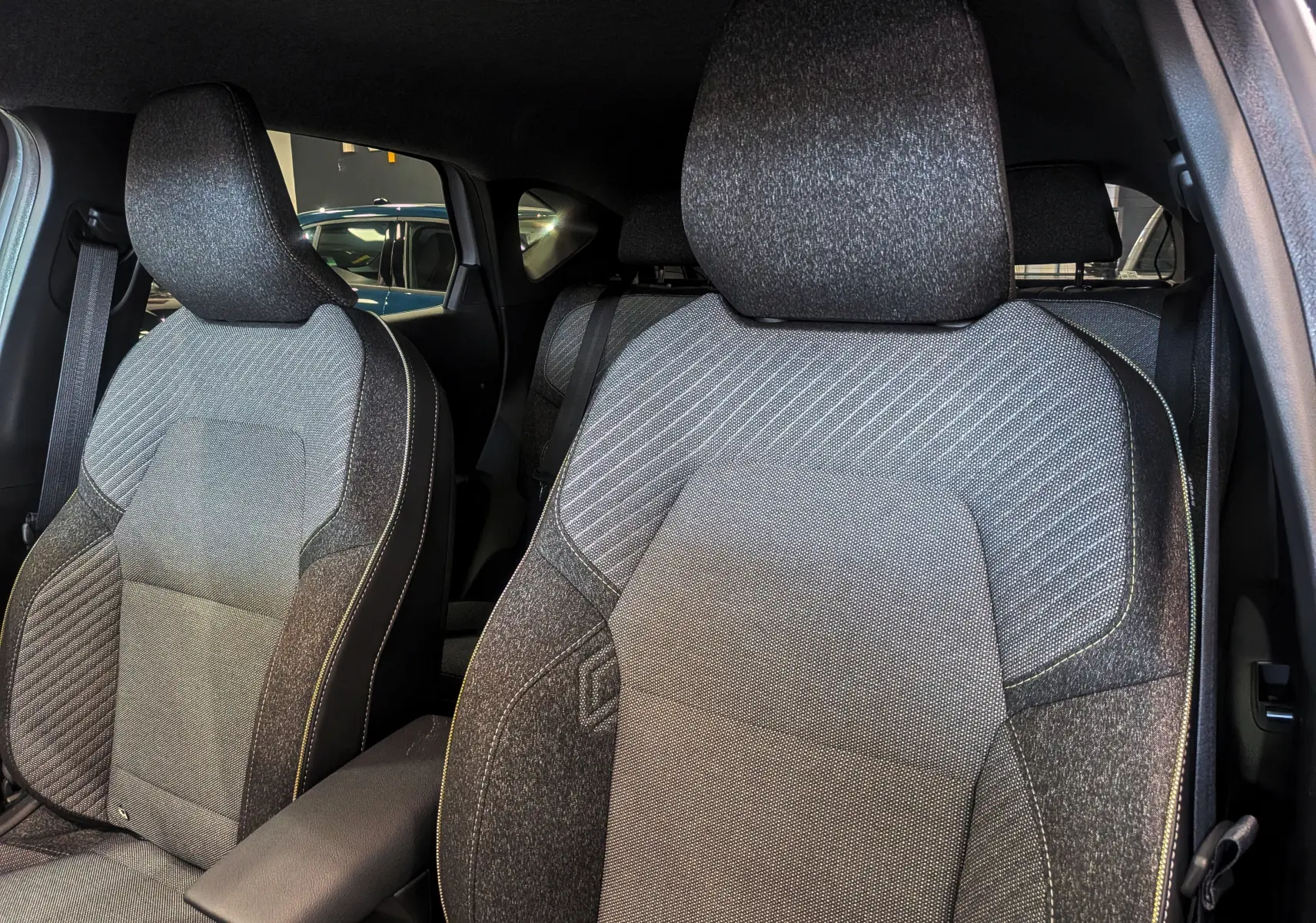 Gros plan sur les sièges avant en tissu gris foncé du Renault Captur Mild Hybrid 160 CH EDC TECHNO 2025.