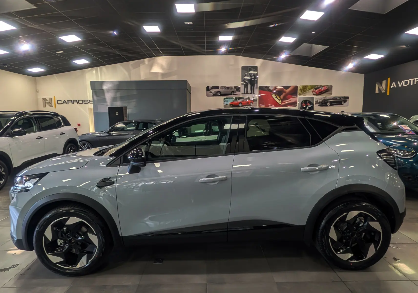 Profil latéral droit du Renault Captur 2025 gris Rafale avec toit noir et jantes bicolores en concession.