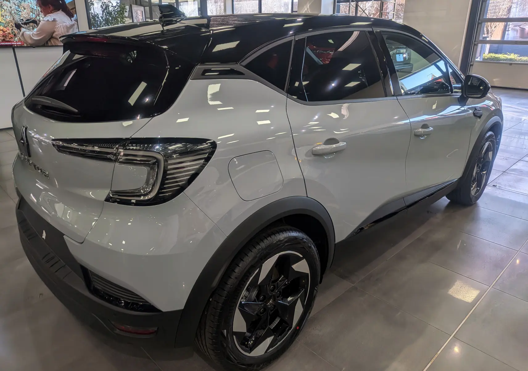 Renault Captur Mild Hybrid gris Rafale avec toit noir, vue 3/4 arrière droit en intérieur showroom.