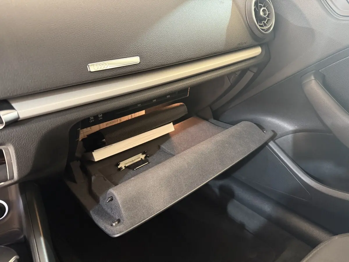 Vue intérieure côté passager de la boîte à gants ouverte de l'Audi A3 Business Line 2018 avec tableau de bord noir.