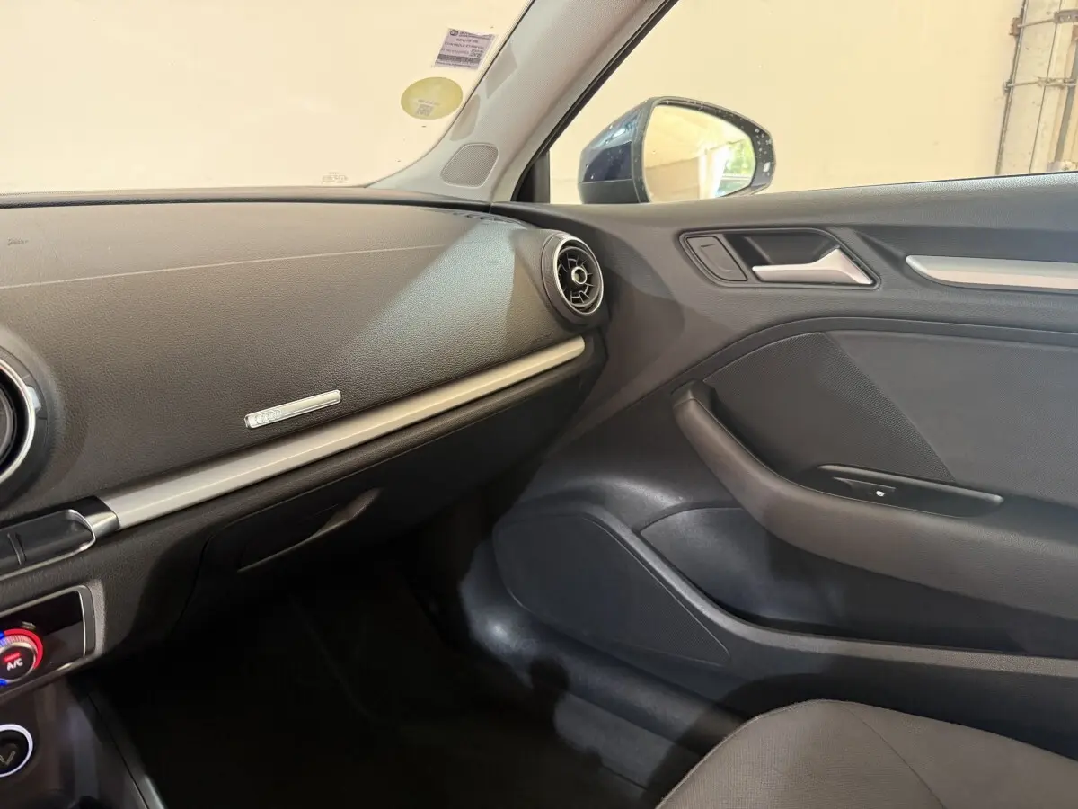 Vue intérieure côté passager de l’Audi A3 2.0 TDI 150 Business Line 2018, tableau de bord et porte en noir.