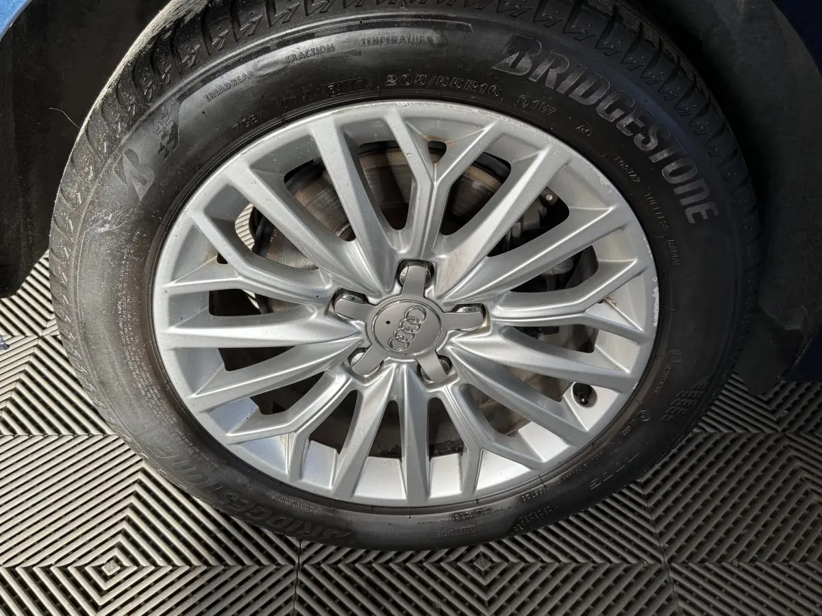 Gros plan sur la jante alliage argentée avec logo Audi, montée sur pneu Bridgestone, sans vue du véhicule.