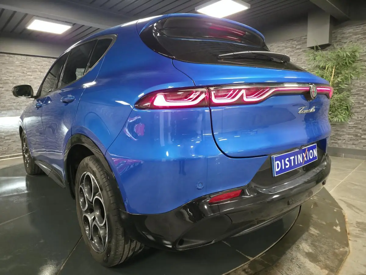 Vue 3/4 arrière gauche d'une Alfa Romeo Tonale bleue avec feux arrière LED et jantes alliage 18 pouces noires.