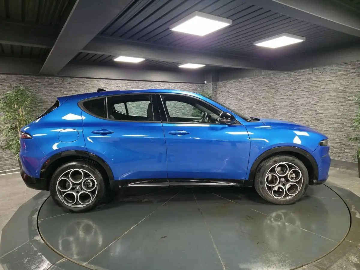 Profil côté gauche d'un Alfa Romeo Tonale bleu métallisé 2025 avec jantes alliage 18 pouces et rétroviseurs noirs brillants.