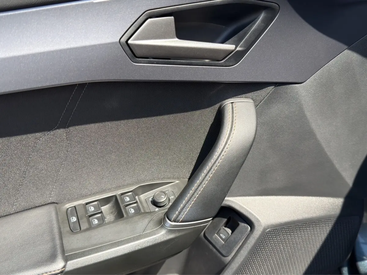 Détail de la porte intérieure côté conducteur gris foncé avec commandes électriques et poignée cuir sur CUPRA Formentor 2025.