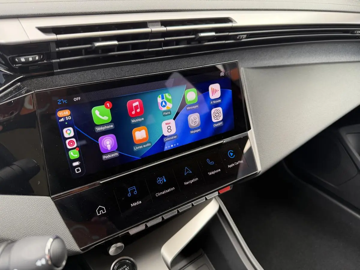 Écran tactile central 10'' du Peugeot 308 SW 2024, affichant Apple CarPlay et commandes multimédia, vue intérieure côté passager.