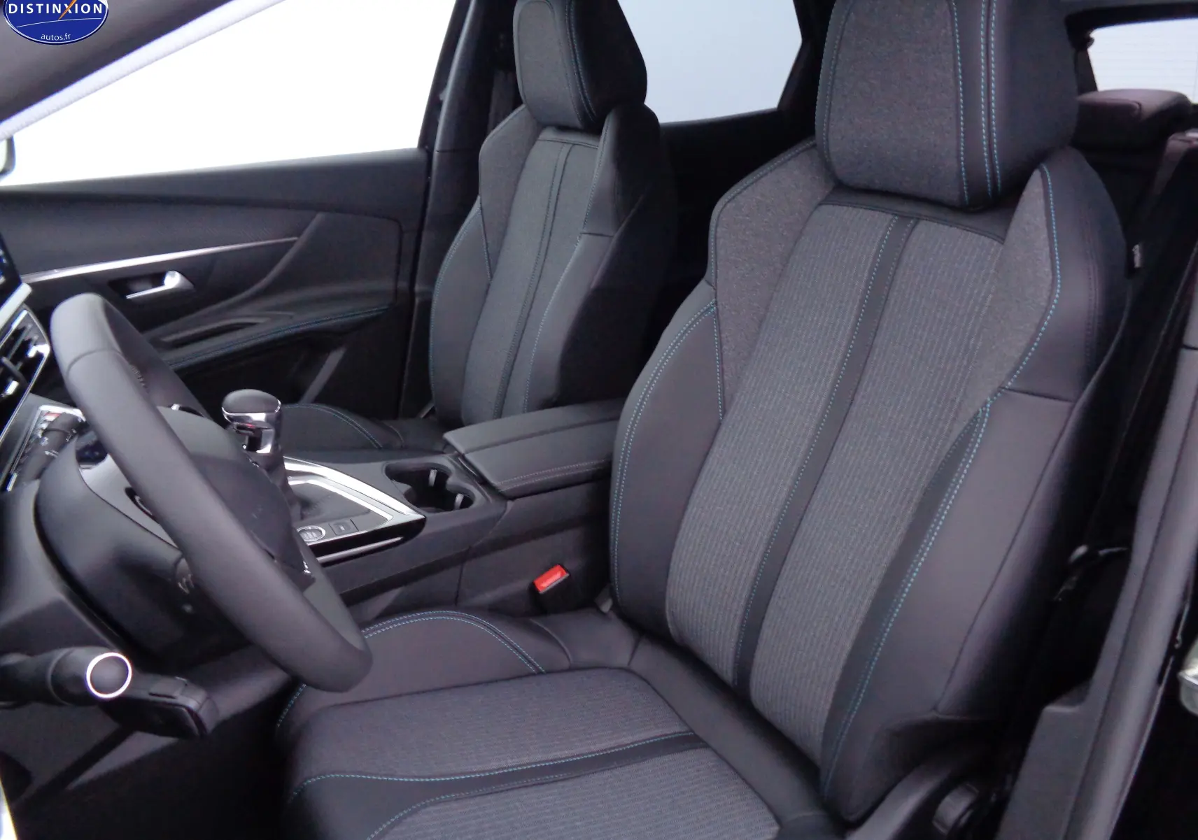 Vue intérieure côté conducteur du Peugeot 3008 2023, sièges en tissu gris et cuir noir avec surpiqûres bleues.