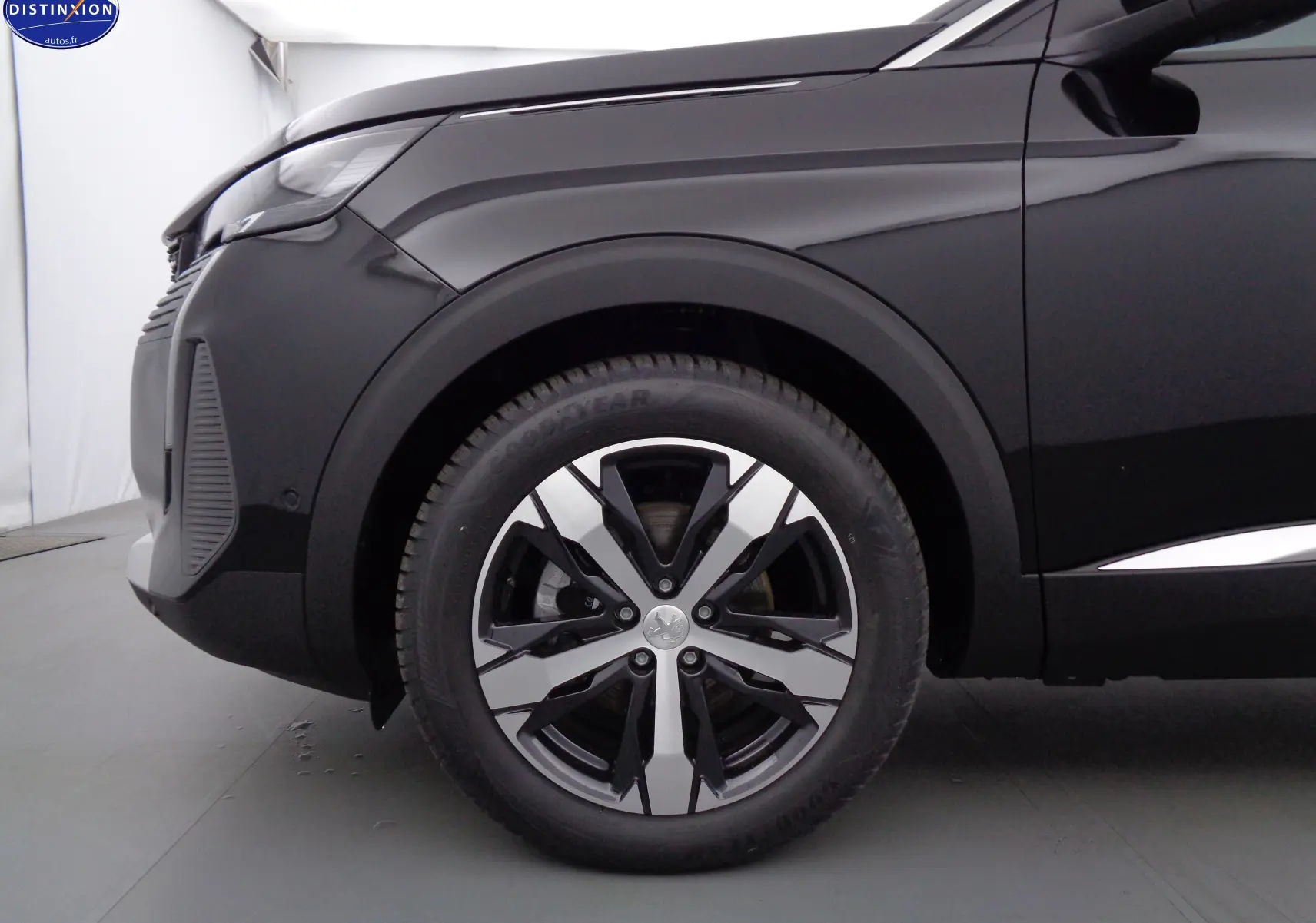 Gros plan sur la roue avant gauche et l'aile d'une Peugeot 3008 noire perle métal, soulignant la jante alliage moderne.