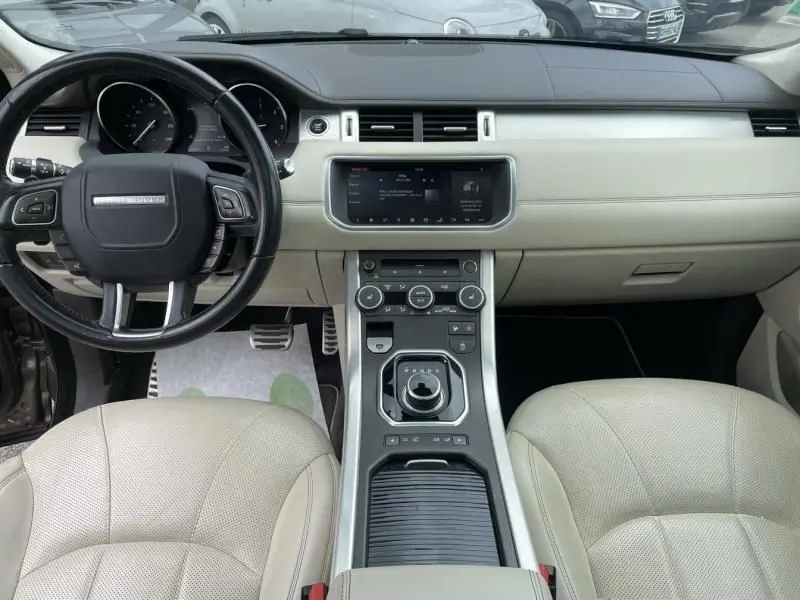 Vue intérieure avant du Range Rover Evoque 2017 avec tableau de bord beige et volant noir au design épuré.