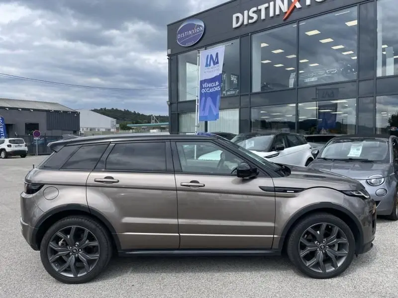 Profil côté gauche d'un Range Rover Evoque TD4 180 Autobiography 2017 marron métal avec toit noir et jantes foncées.