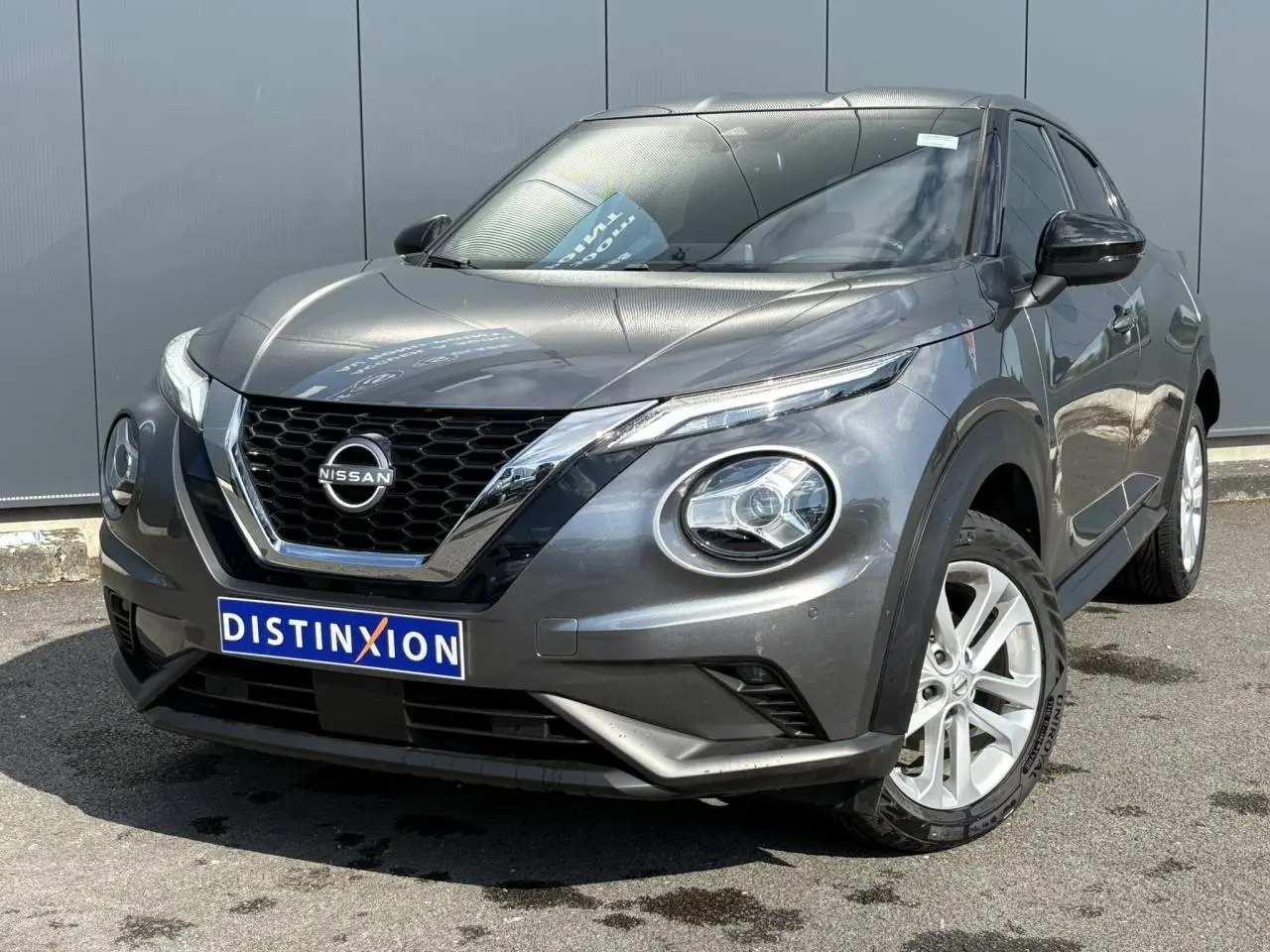 Nissan Juke gris Dark Metal en 3/4 avant droit, avec calandre chromée et jantes alliage 17 pouces visibles.