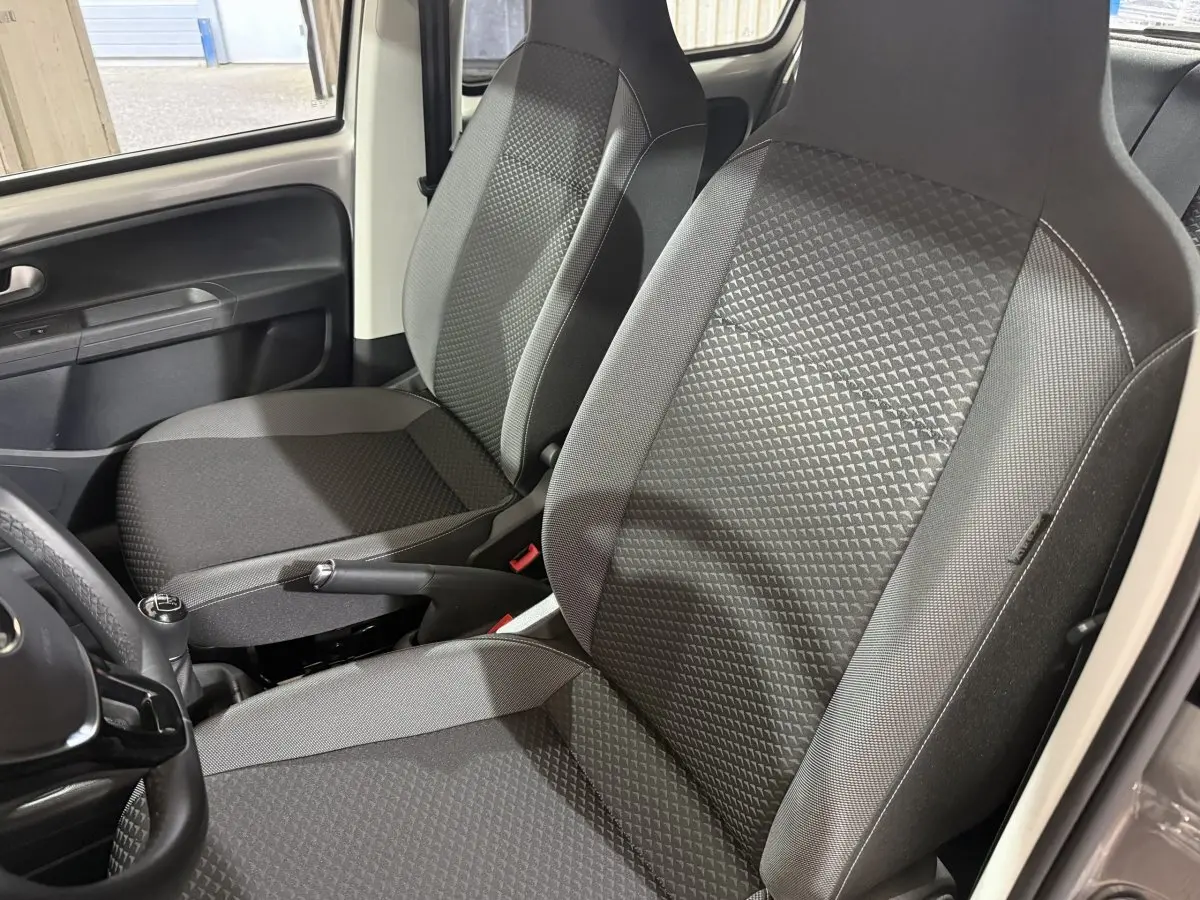 Vue intérieure rapprochée des sièges avant gris foncé et du levier de vitesse manuel d'une Volkswagen Up 2022.