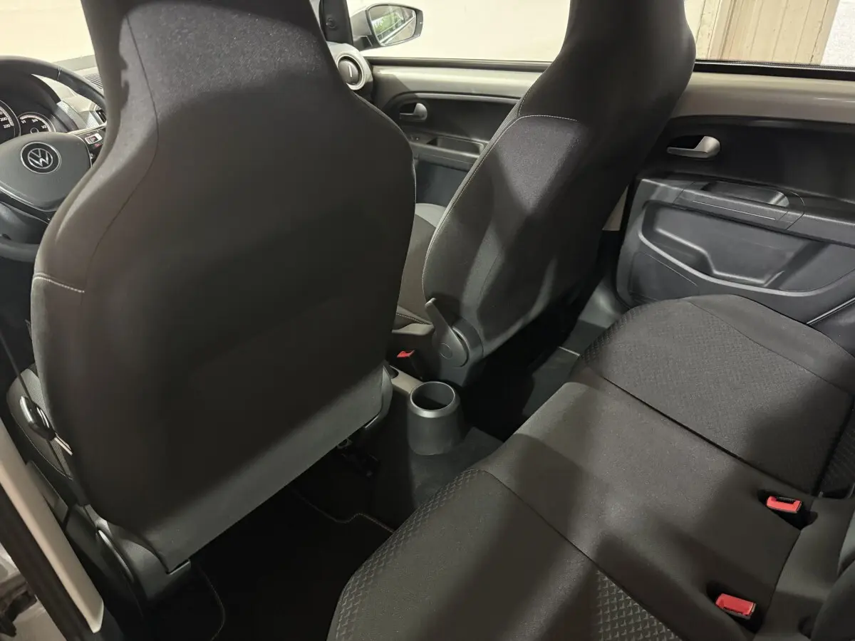 Vue intérieure arrière du Volkswagen Up 1.0 65 Active, sièges noirs et console centrale compacte visible.