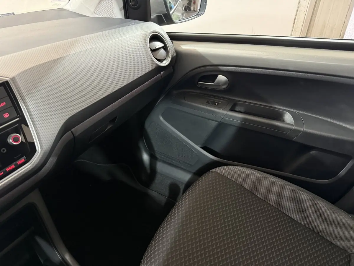 Vue intérieure côté passager du Volkswagen Up 1.0 65 Active 2022, tableau de bord gris clair et siège tissu gris foncé.