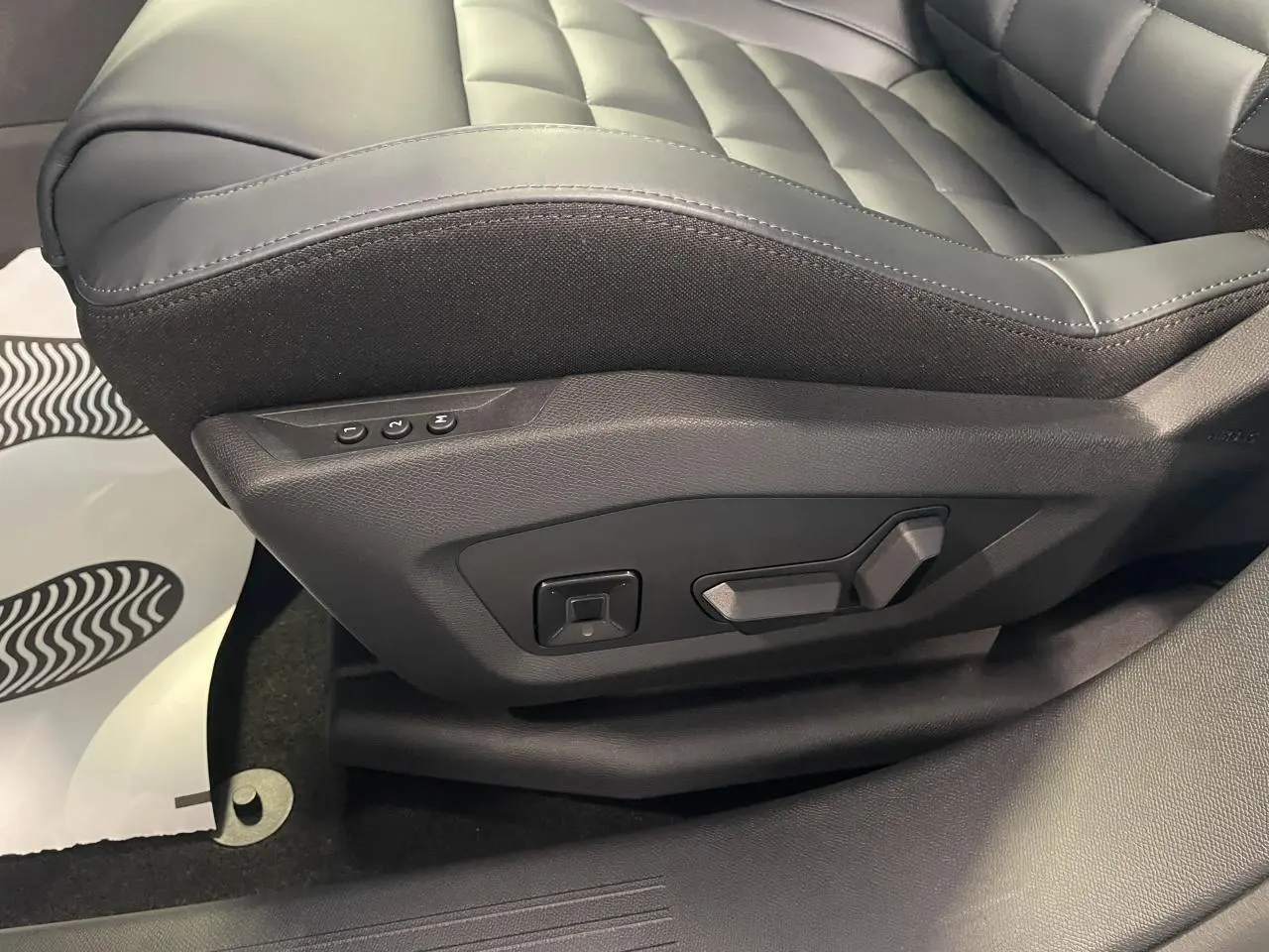 Détail du siège conducteur noir matelassé avec commandes électriques sur le côté gauche dans un Citroën C5 Aircross.