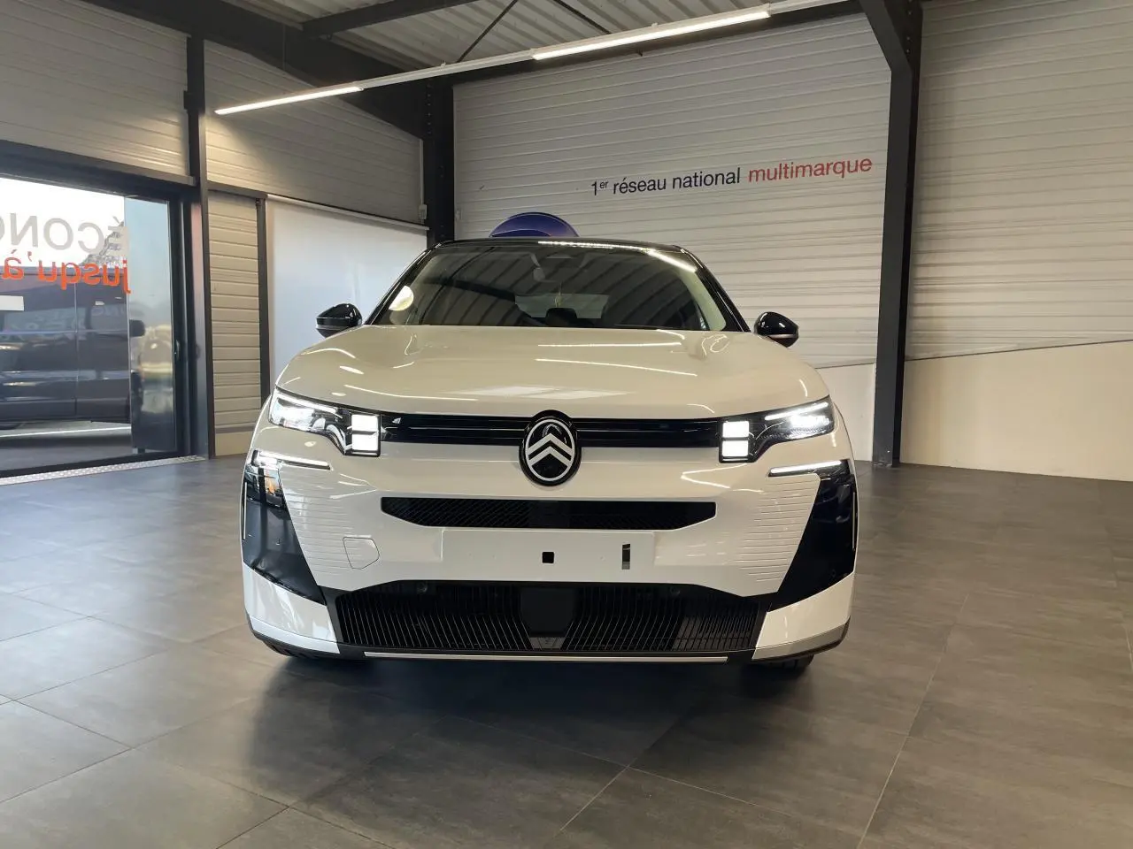 Vue avant d'un Citroën C5 Aircross blanc Okenite avec toit noir et calandre noir brillant en showroom.