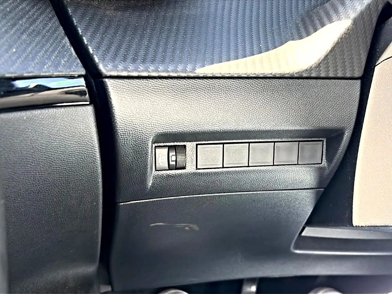 Détail intérieur côté conducteur du tableau de bord noir avec commande de réglage d’intensité lumineuse sur Peugeot 2008 gris.