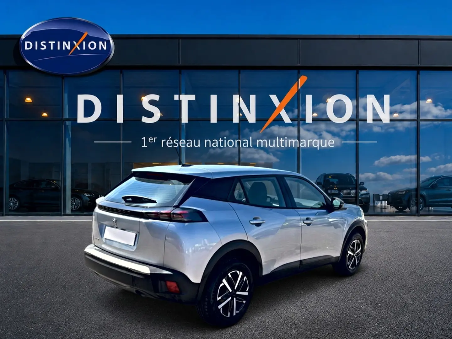 Peugeot 2008 gris vue 3/4 arrière droit, avec becquet et feux arrière à LED visibles.