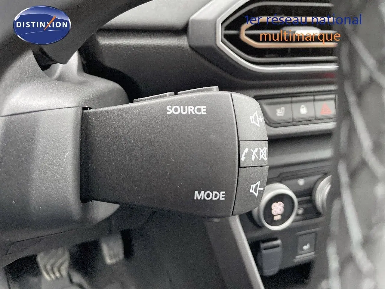 Gros plan sur la commande audio au volant du Dacia Jogger noir nacré, avec tableau de bord en arrière-plan.