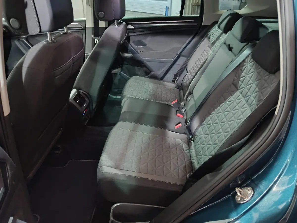 Vue intérieure côté droit sur la banquette arrière grise du Volkswagen Tiguan bleu, avec détails de la porte et sièges.