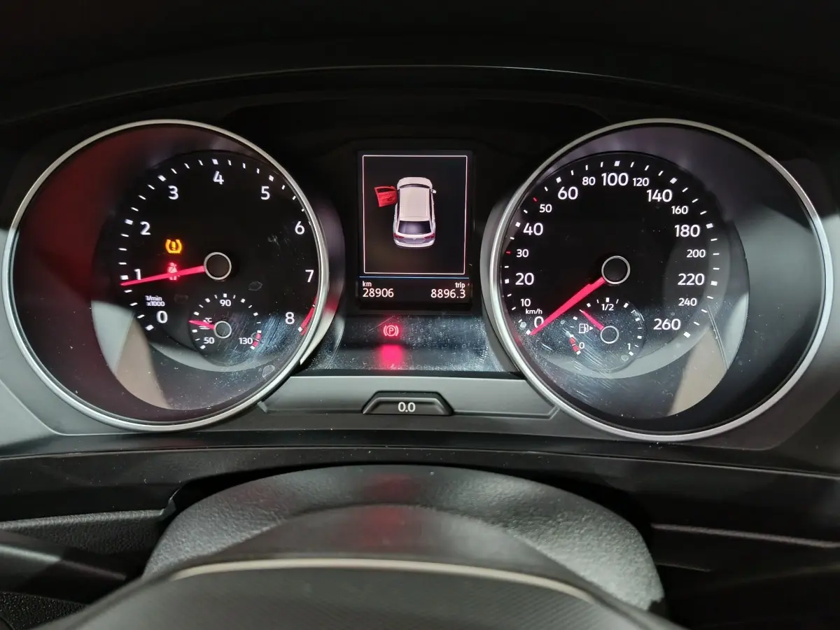 Vue rapprochée du tableau de bord du Volkswagen Tiguan bleu, affichant compte-tours, vitesse et alertes ouvertes.