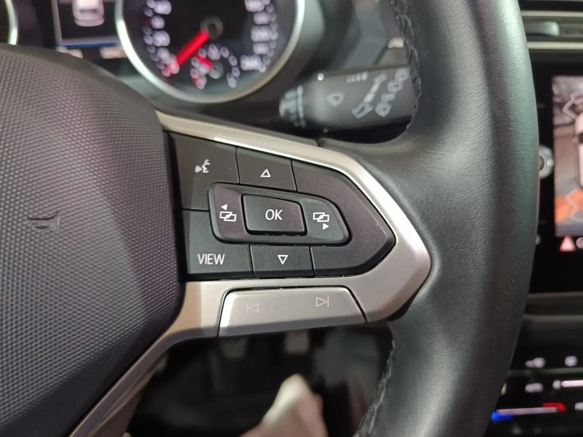 Gros plan sur le volant cuir noir multifonctions du Volkswagen Tiguan 2021, avec commandes intégrées et tableau de bord partiel.