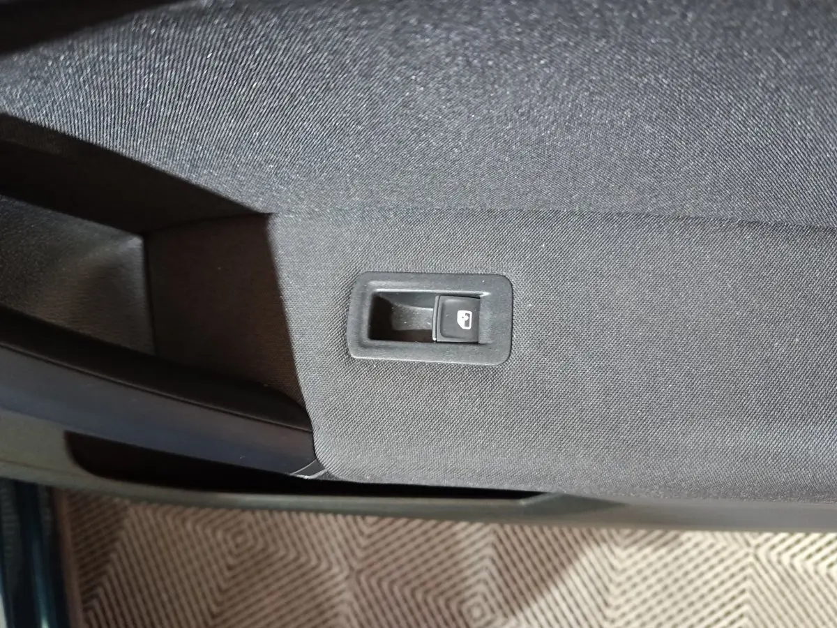 Gros plan sur le bouton de verrouillage des portes sur la garniture intérieure noire d'une Volkswagen Tiguan bleu.