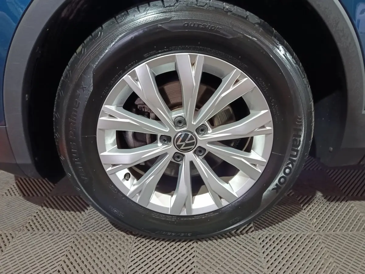 Gros plan sur la roue avant droite du Volkswagen Tiguan bleu, mettant en valeur la jante alliage argentée et le pneu Hankook.