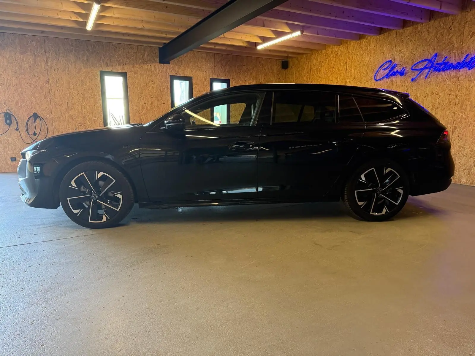 Peugeot 508 SW noire vue de profil côté gauche, avec jantes alliage bi-ton et toit noir brillant.