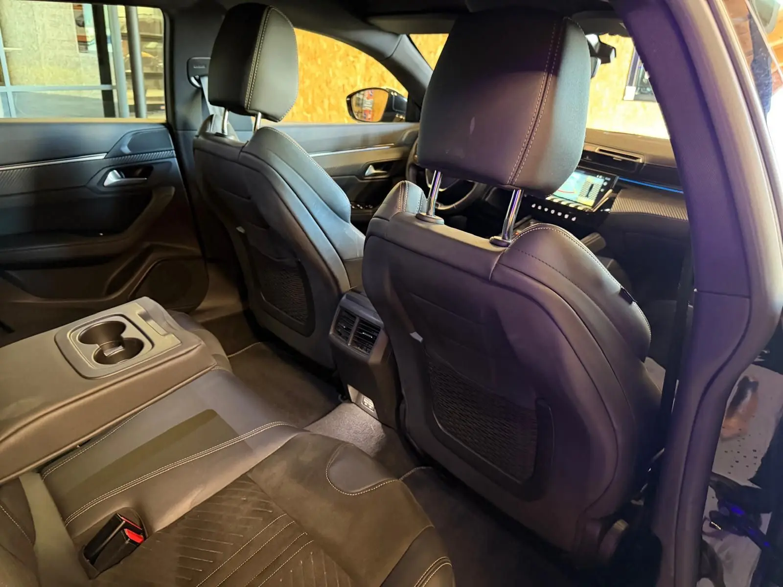 Vue intérieure arrière de la Peugeot 508 SW 2024, sièges en Alcantara noir avec surpiqûres et accoudoir central rabattable.