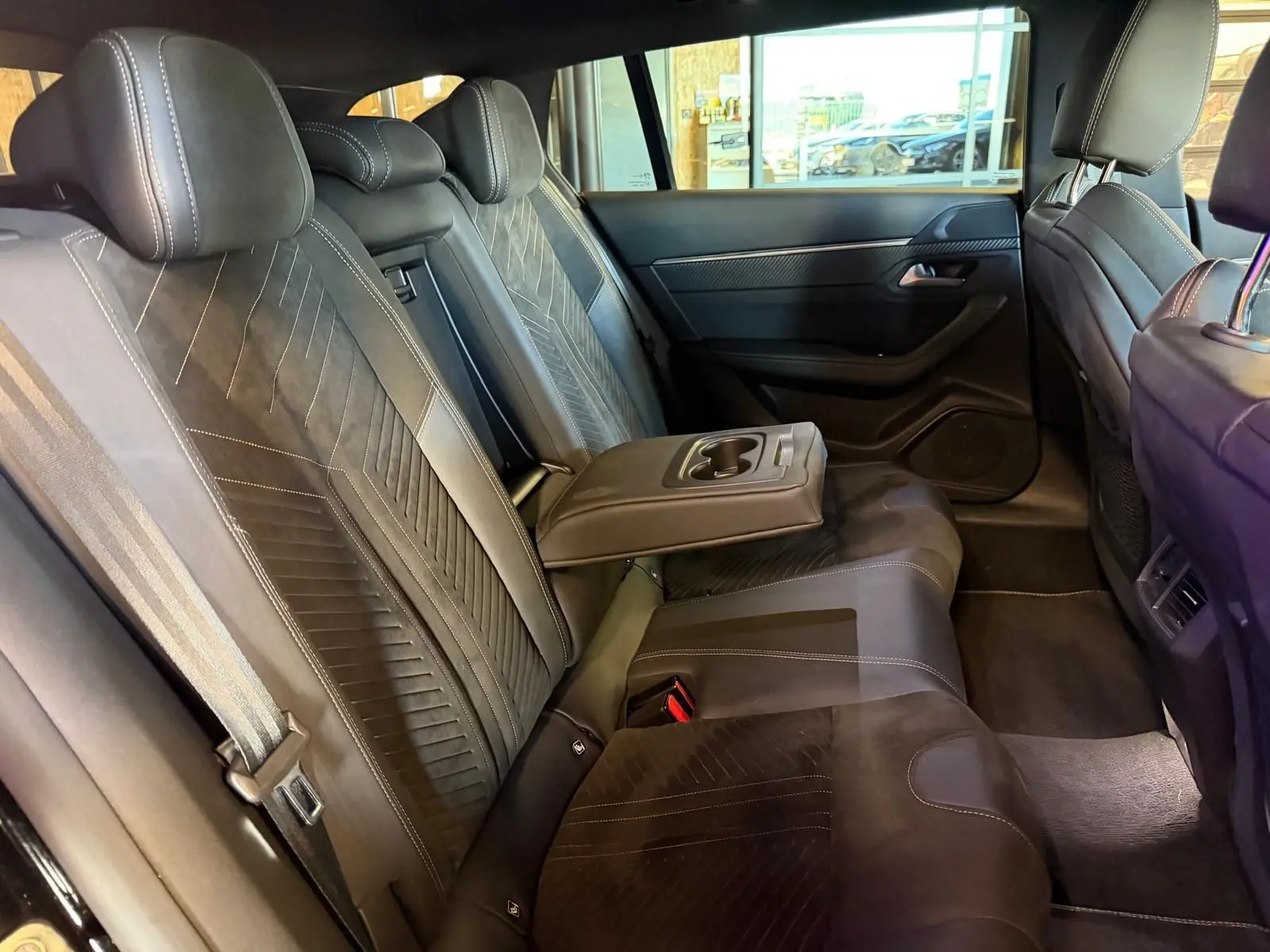Vue intérieure côté droit des sièges arrière noirs en Alcantara avec accoudoir central et surpiqûres Aikinite Peugeot 508 SW 2024.