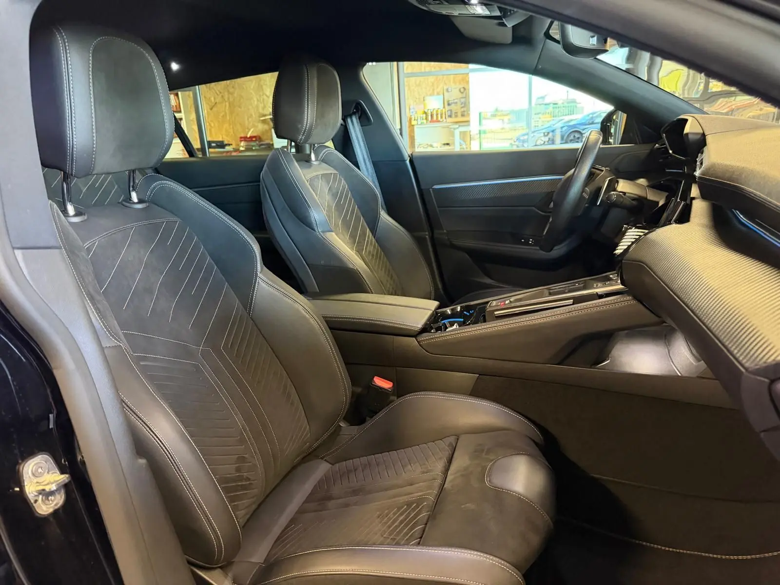 Vue intérieure côté conducteur de la Peugeot 508 SW noire, mettant en valeur les sièges Alcantara et la console centrale moderne.