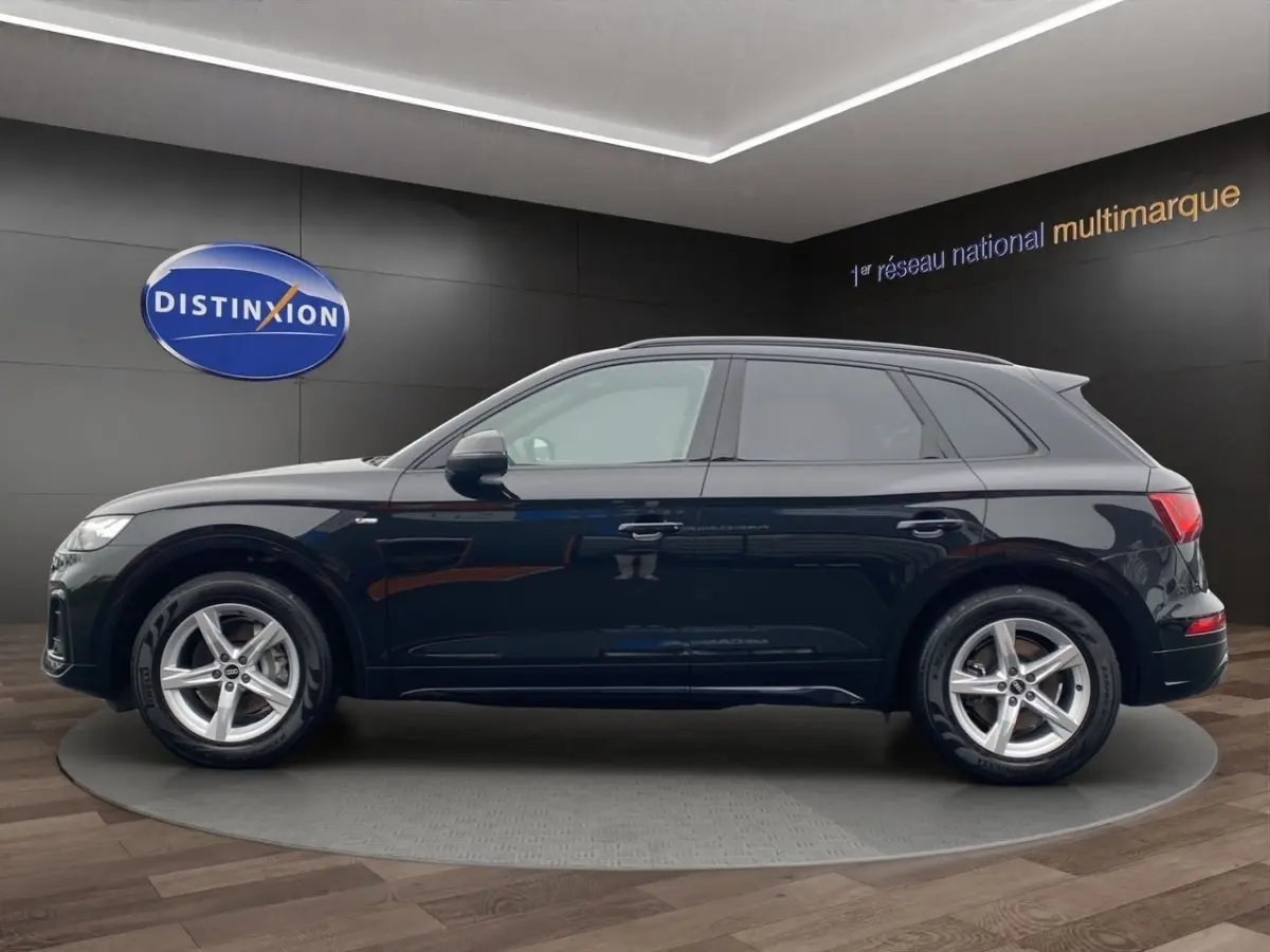 Audi Q5 noir vue de profil côté gauche, avec jantes alliage et badge S line visible sur l'aile avant.