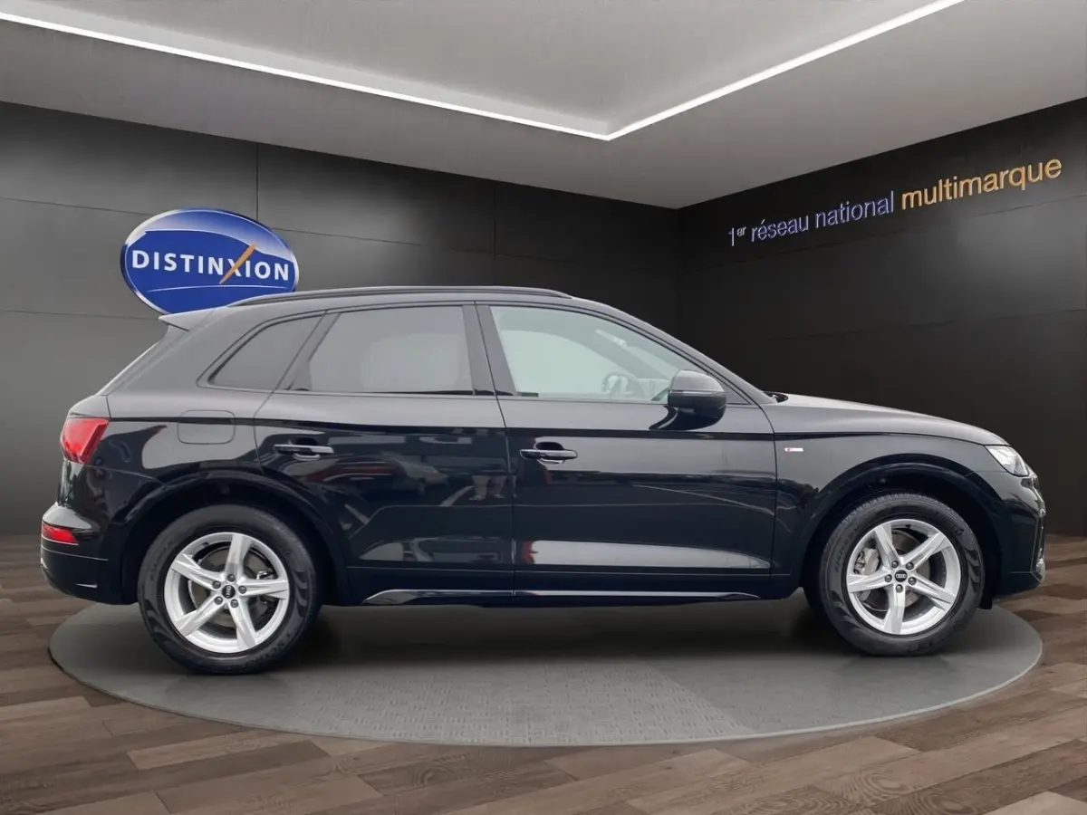 Audi Q5 noir en vue profil côté gauche, avec jantes alliage et badge S Line visible sur l'aile avant.