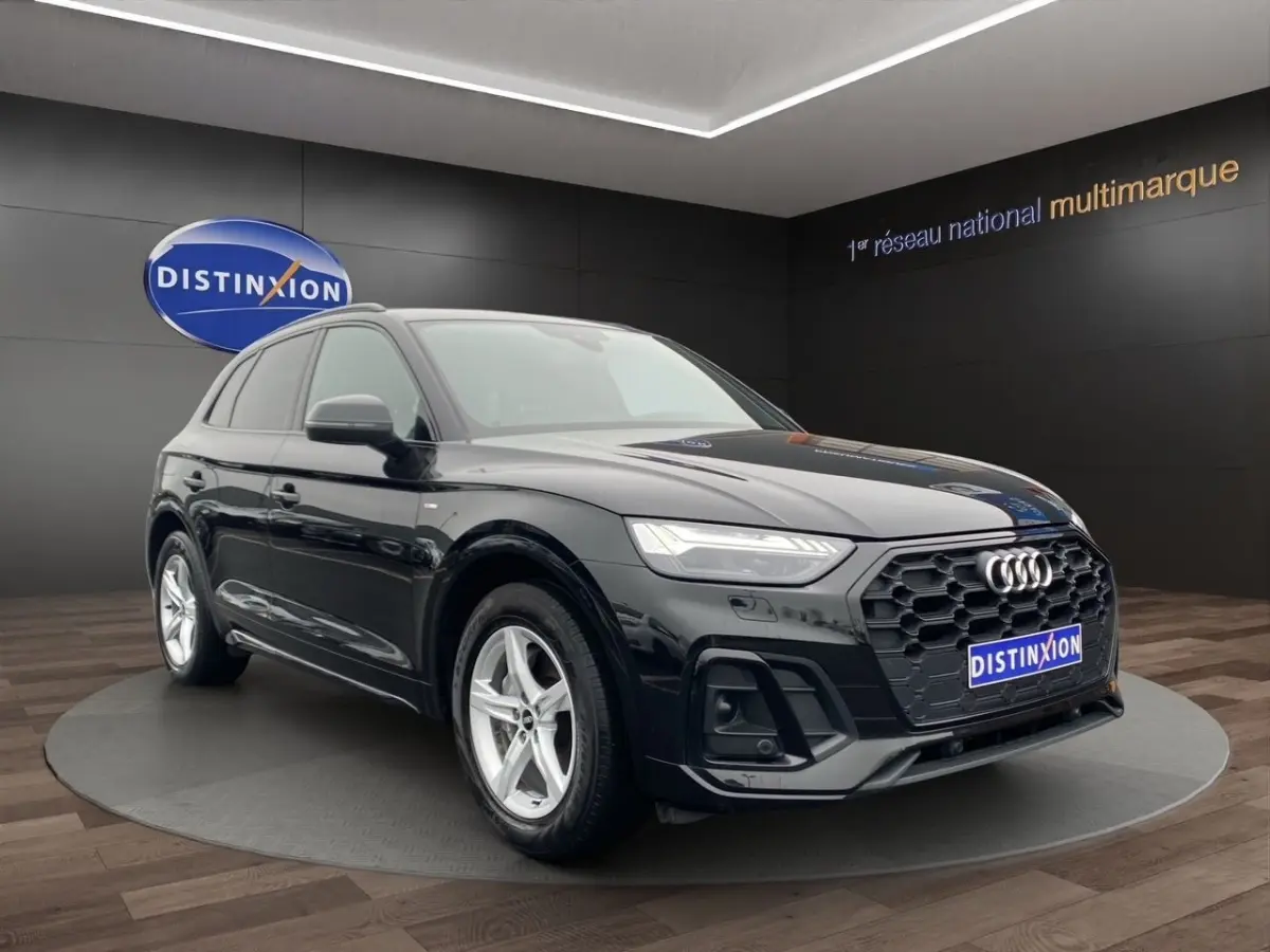 Audi Q5 noir en 3/4 avant droit, avec calandre hexagonale noire et jantes argentées cinq branches.