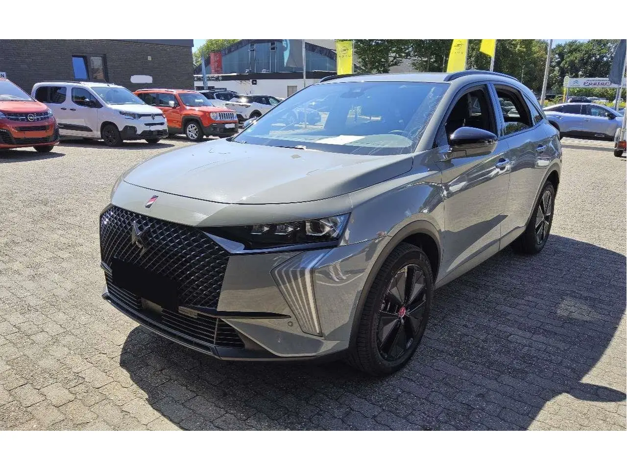 DS7 gris laqué vu en 3/4 avant droit, avec calandre noire texturée et jantes alliage noires distinctives.