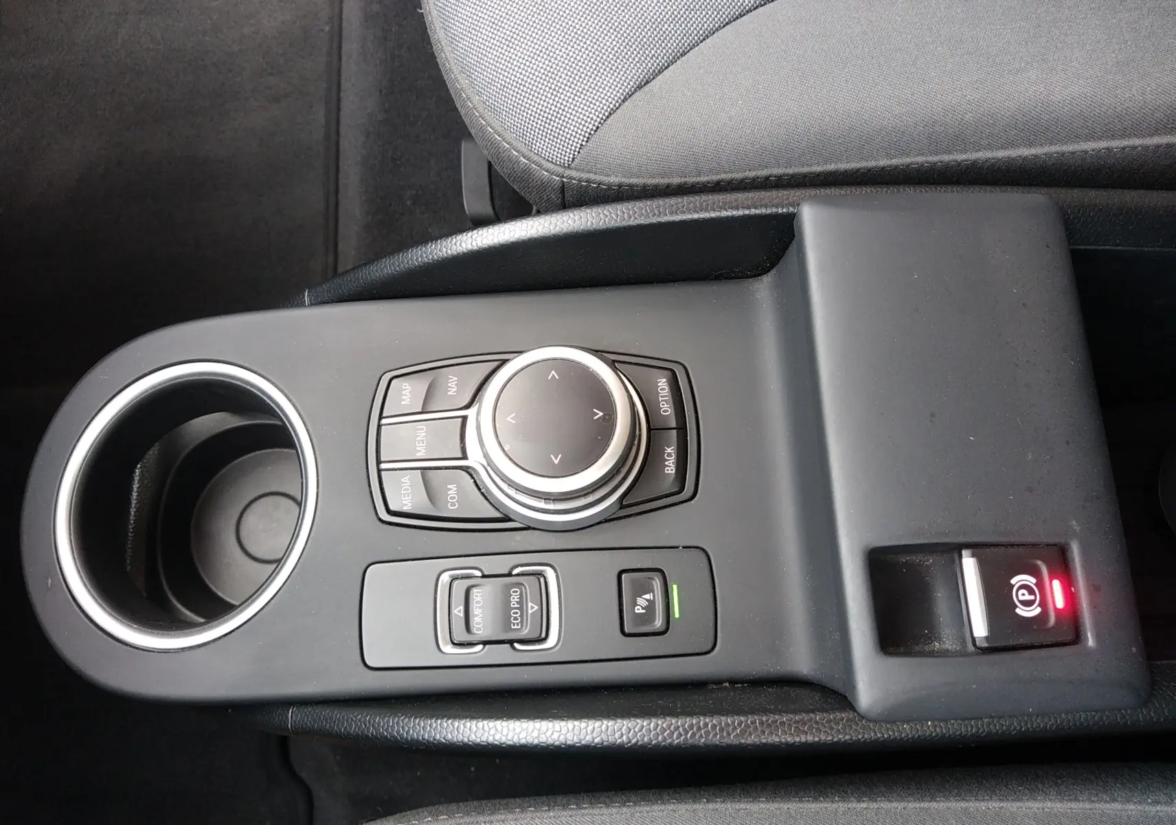 Vue rapprochée de la console centrale noire avec commandes multimédia et frein à main électrique d'une BMW i3 2022.