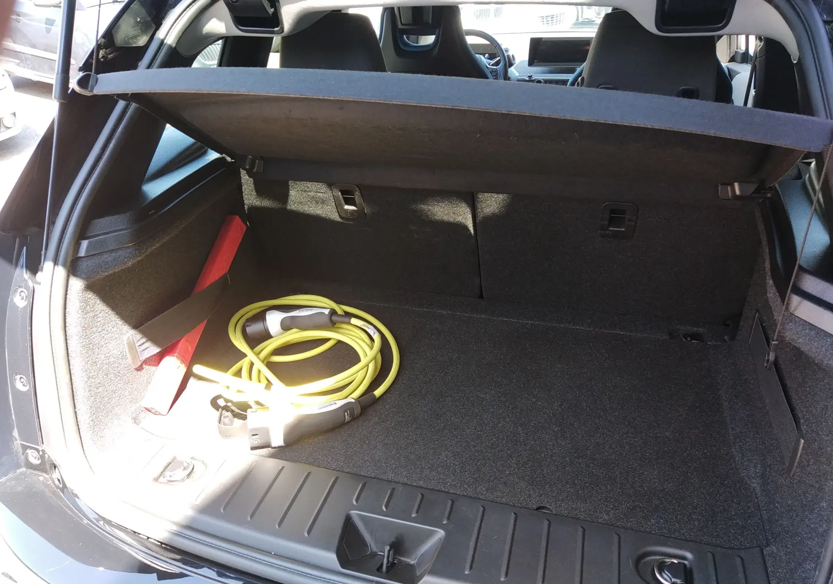 Coffre ouvert d'une BMW i3 bleu électrique 2022, avec câble de recharge jaune visible à l'intérieur.