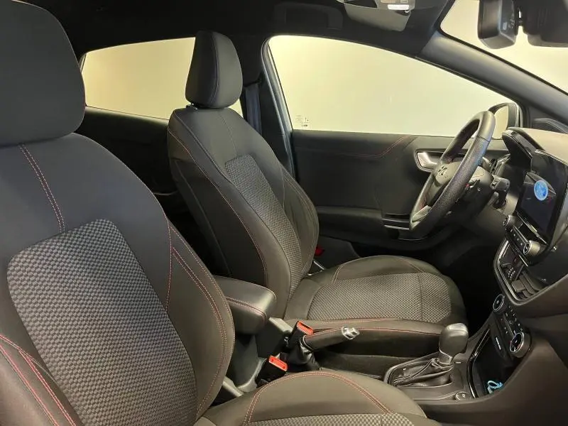 Intérieur avant droit du Ford Puma 2021 avec sièges sport noirs à surpiqûres rouges et tableau de bord moderne.