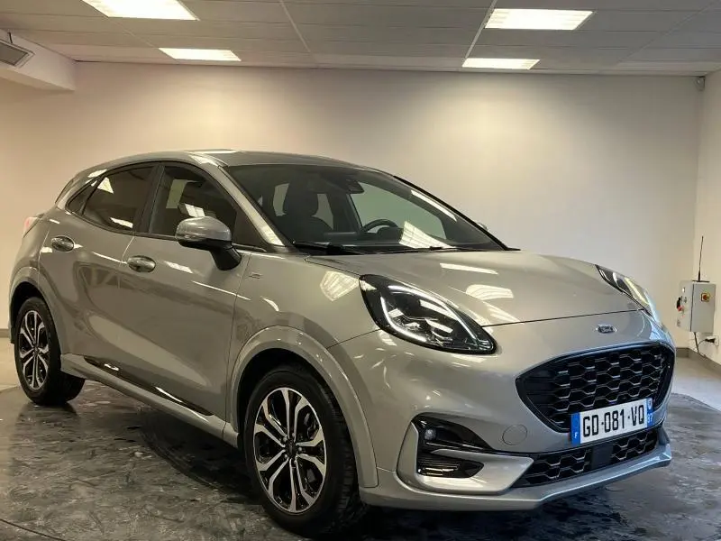 Ford Puma gris Solar métallisée vue 3/4 avant droit en intérieur avec calandre noire et jantes alliage.