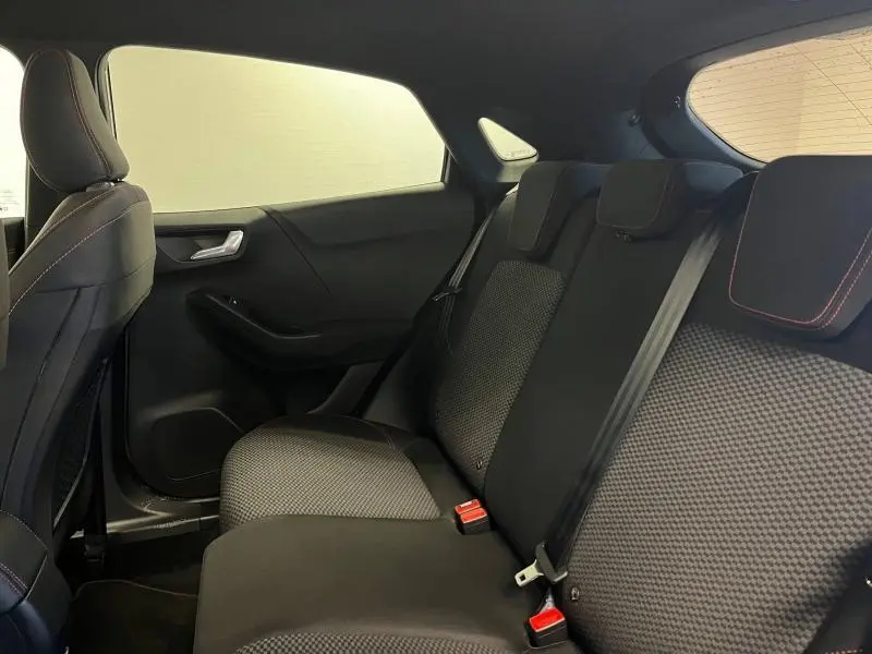 Vue intérieure du siège arrière droit du Ford Puma 1.0 EcoBoost gris avec tissu noir et surpiqûres rouges.