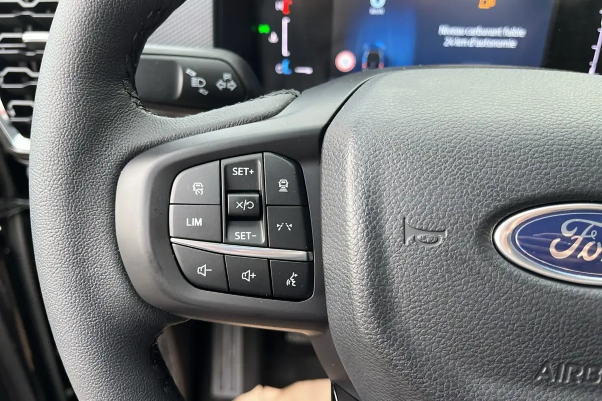 Gros plan sur le volant cuir multifonctions noir du Ford Ranger 2025 avec commandes intégrées à gauche.