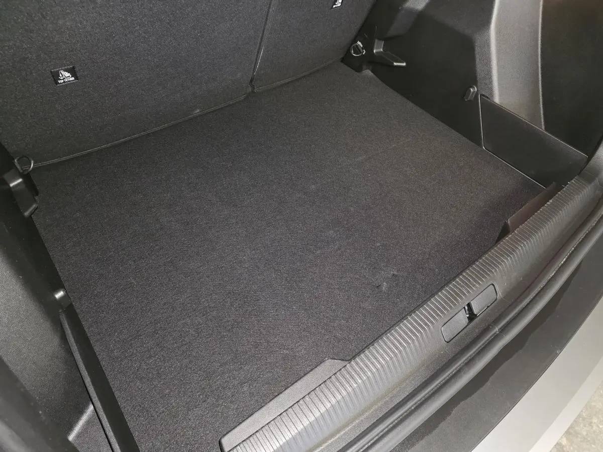 Coffre ouvert du Peugeot 2008 gris, vue plongeante sur le tapis de coffre et seuil de chargement.