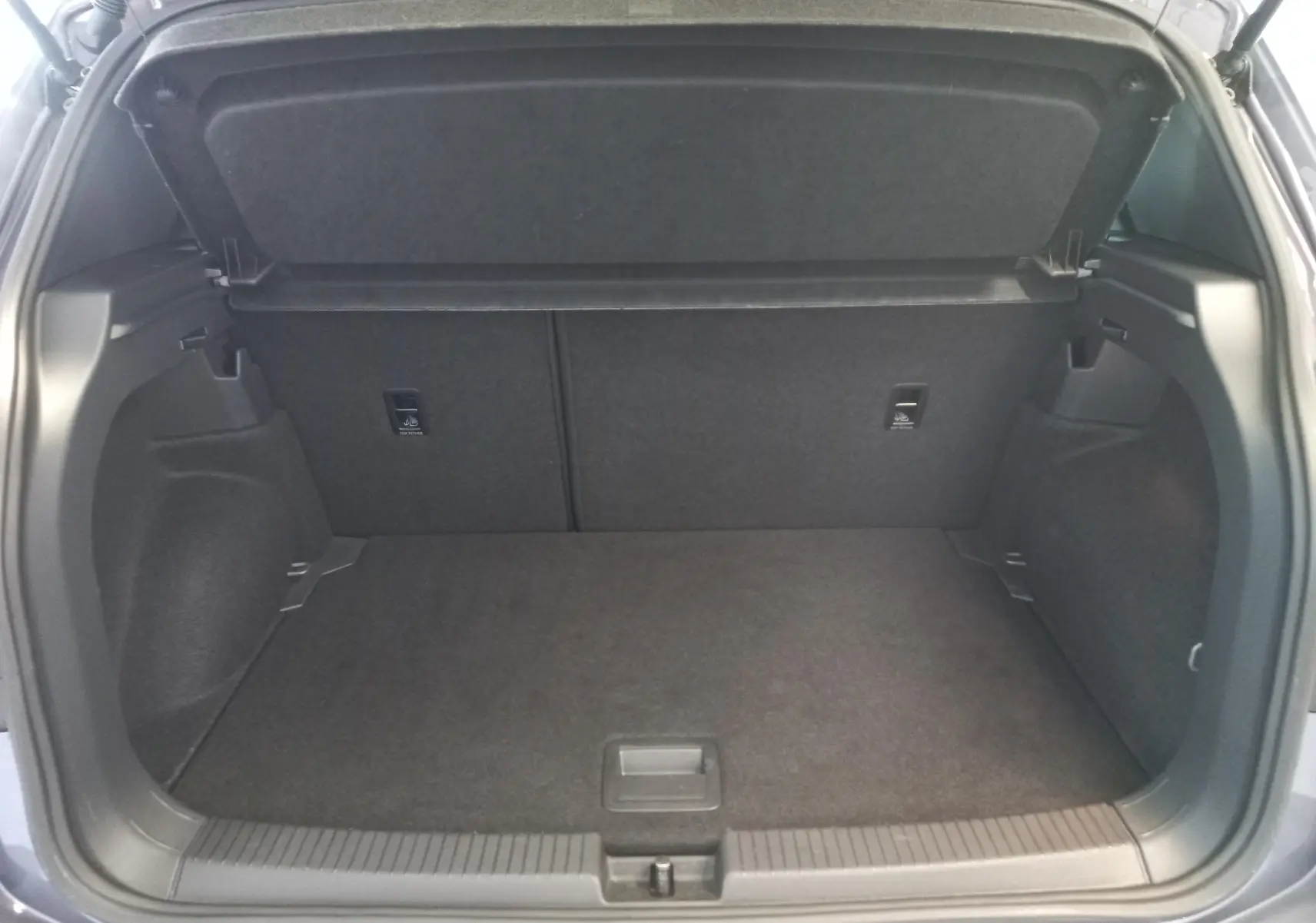 Coffre ouvert du Volkswagen T-Cross gris cendré, vue arrière montrant l'espace de chargement vide et la tablette cache-bagages.
