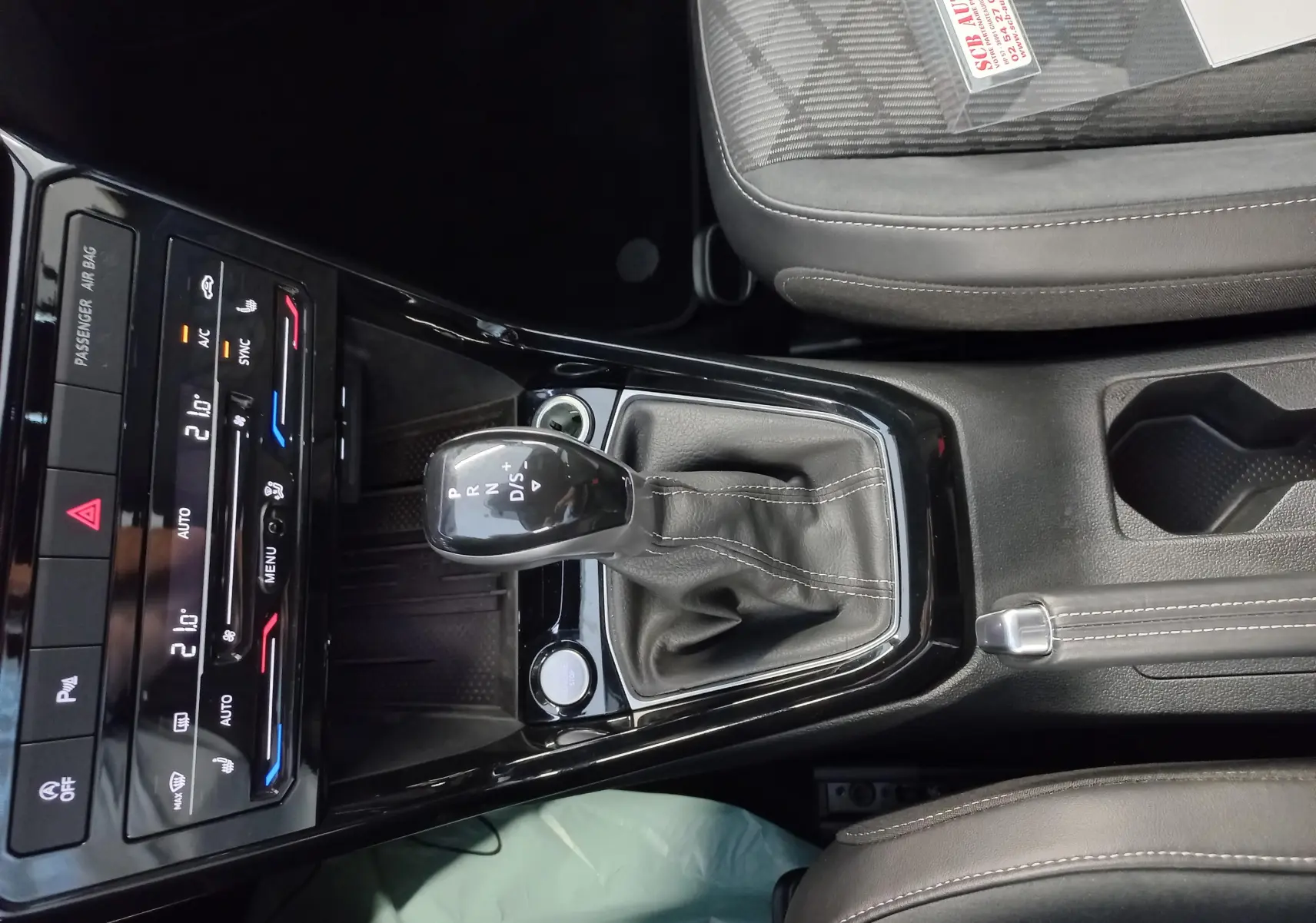 Vue rapprochée de la console centrale du Volkswagen T-Cross 2025 avec levier de vitesses DSG et sellerie grise.
