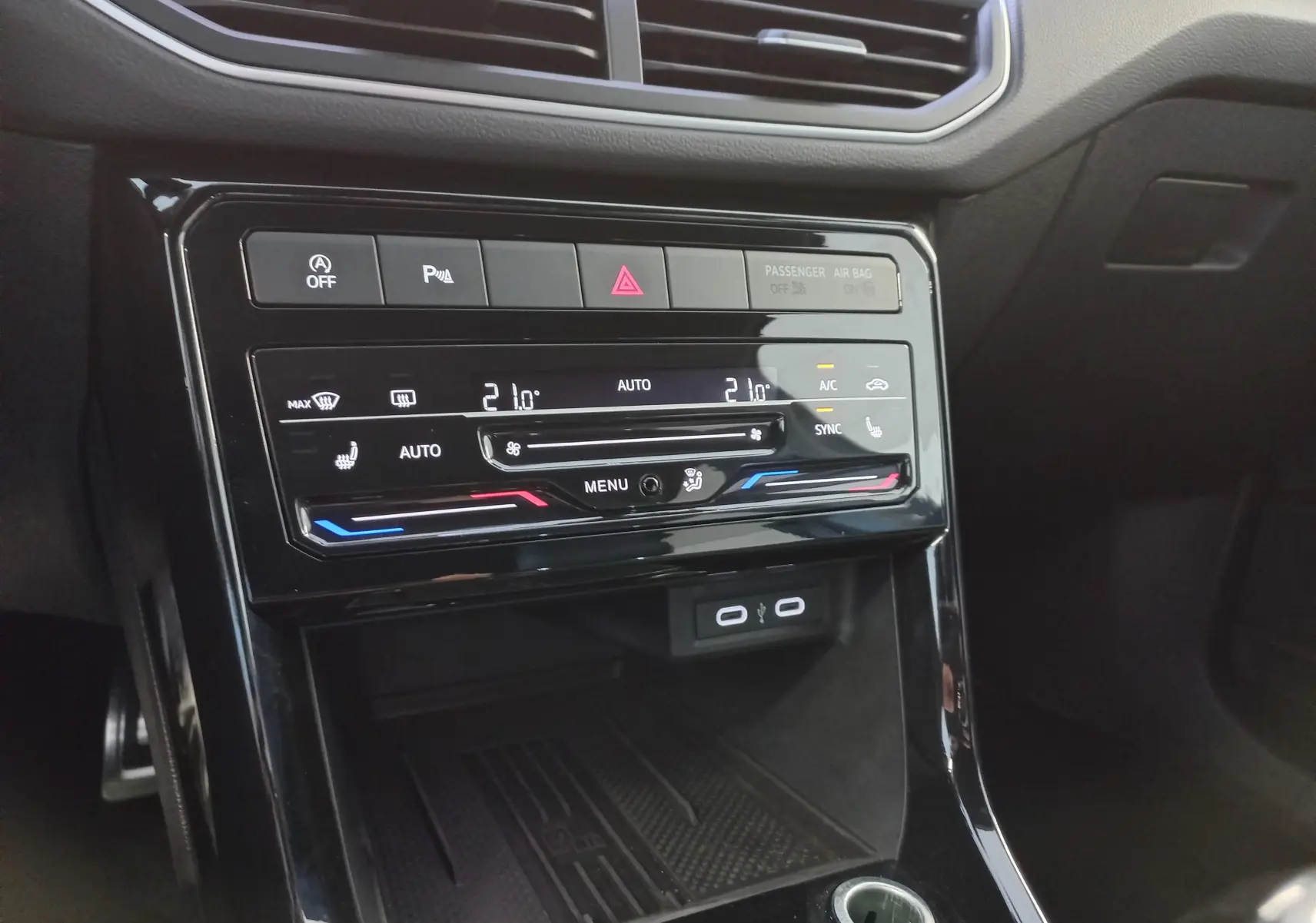 Vue rapprochée de la console centrale du Volkswagen T-Cross 1.0 TSI R-Line, avec commandes climatisation et ports USB visibles.
