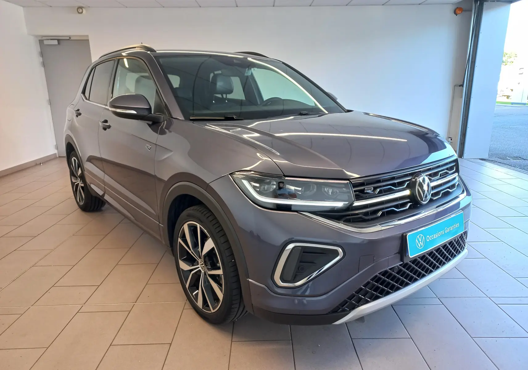 Volkswagen T-Cross 2025 gris cendré en 3/4 avant droit, avec jantes alliage 18 pouces et finition R-Line Edition.