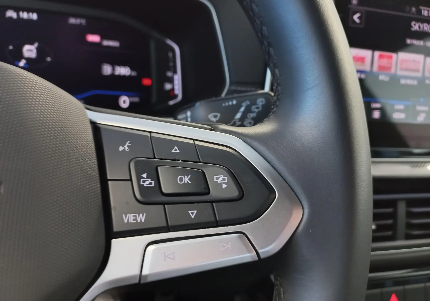 Gros plan sur les commandes au volant côté gauche du Volkswagen T-Cross 2025 gris cendré, version R-Line Edition.