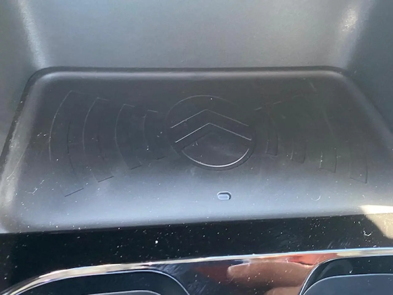 Détail du chargeur sans fil avec logo Citroën embossé, intérieur noir brillant du C3 Aircross 2026.