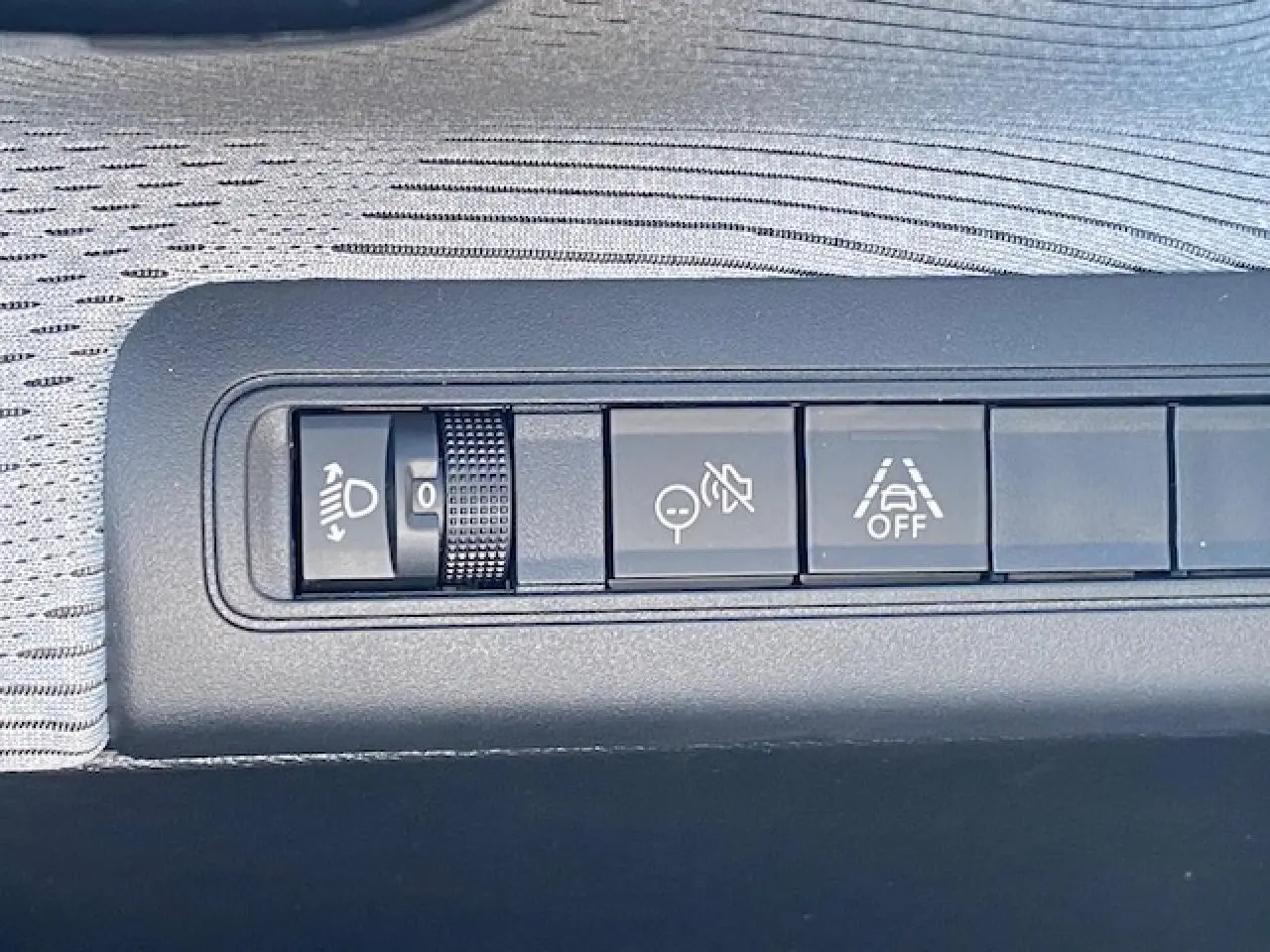 Gros plan sur les commandes d'assistance à la conduite sur la planche de bord grise du Citroën C3 Aircross 2026.